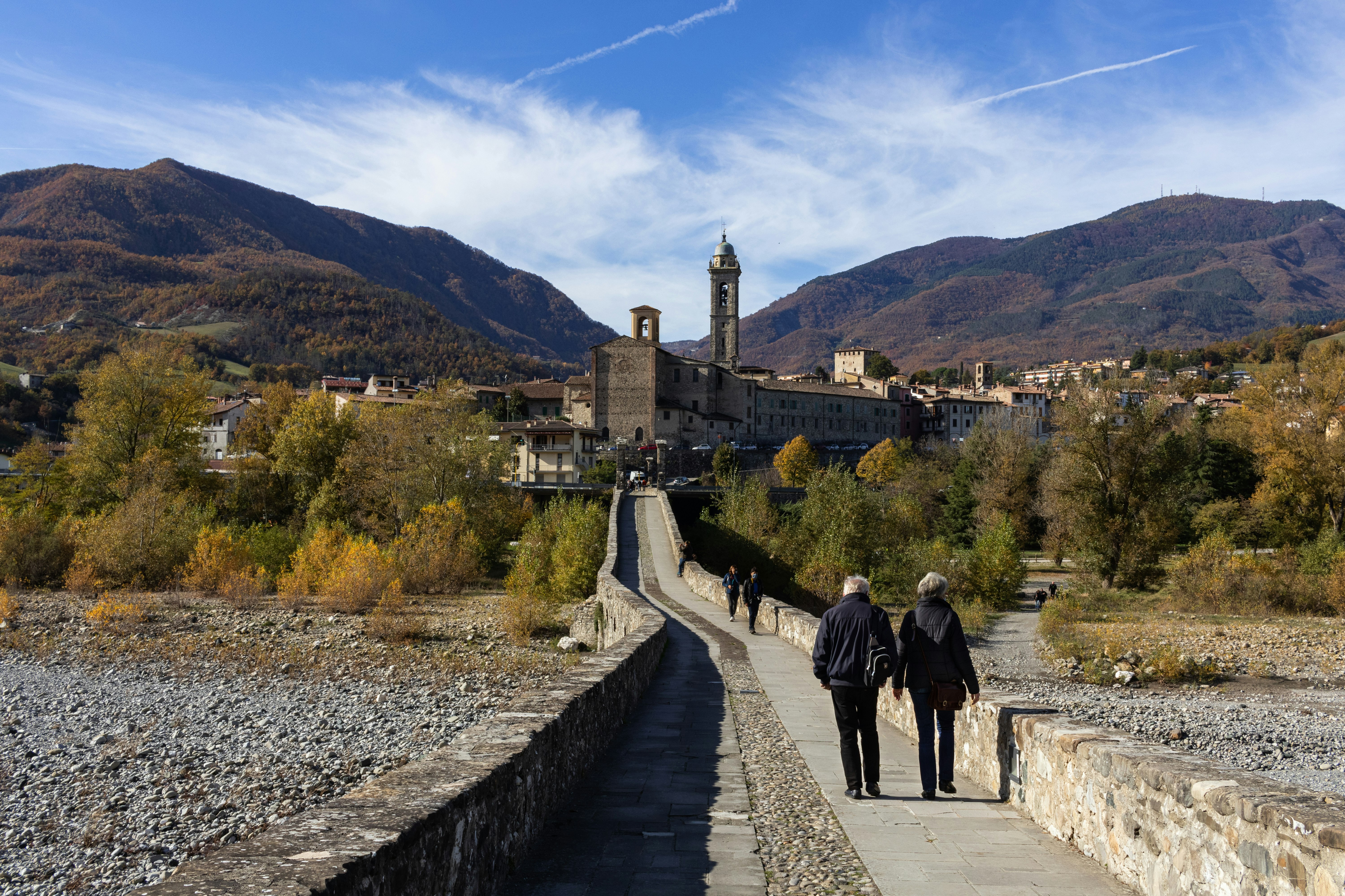 man and woman walking on pathway near brown concrete building during daytime